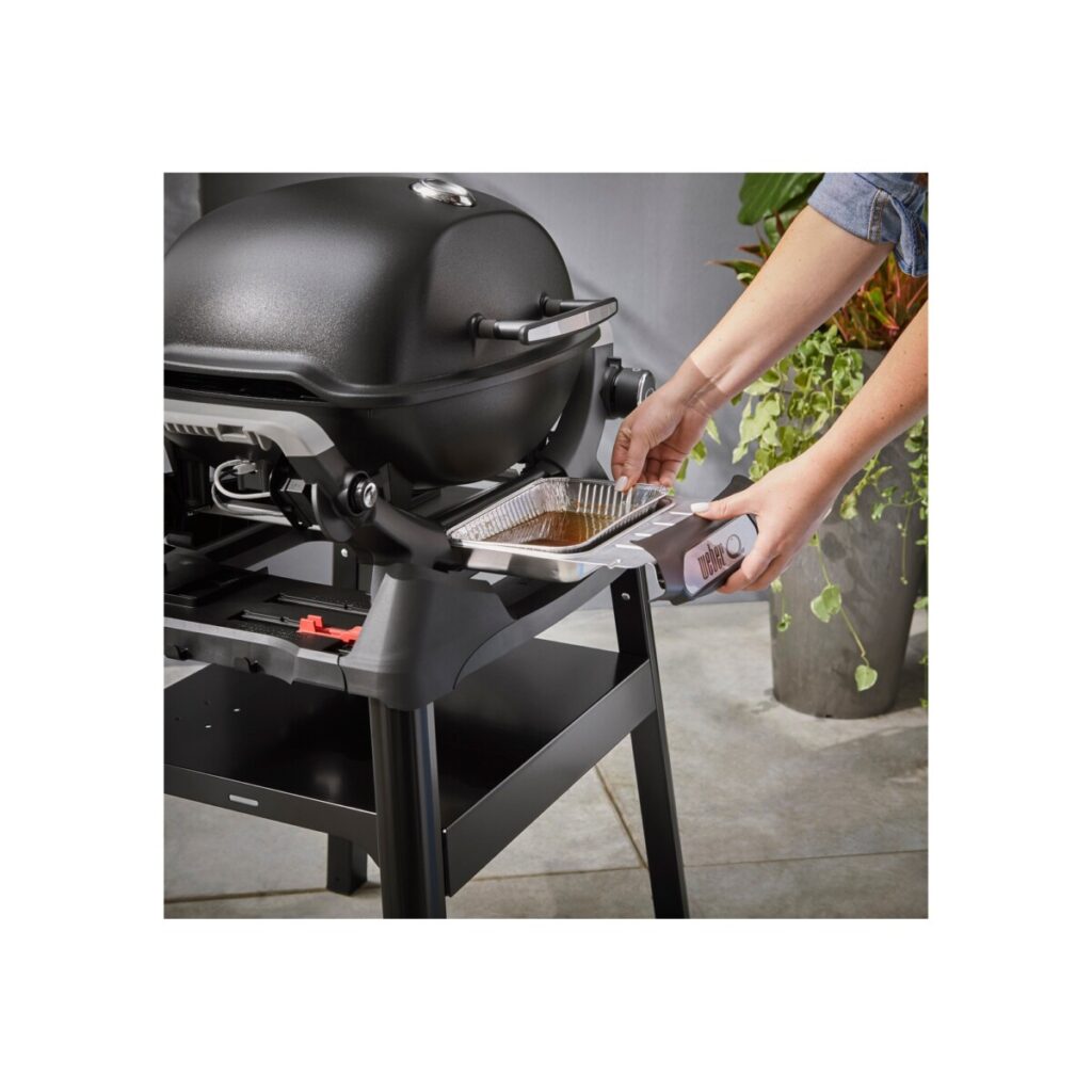 Persona limpiando barbacoa con bandeja de goteo.