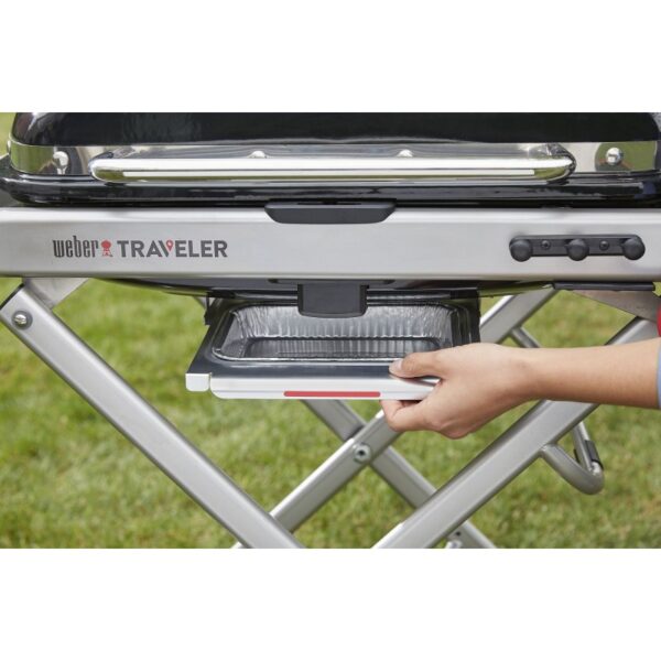 Persona usando barbacoa portátil Weber Traveler.