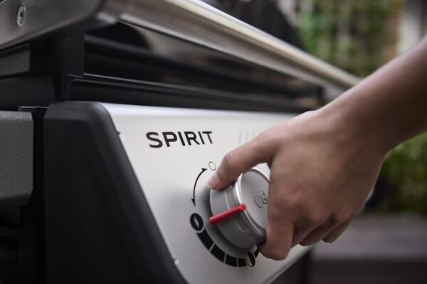 Mano ajustando perilla en una barbacoa Spirit.