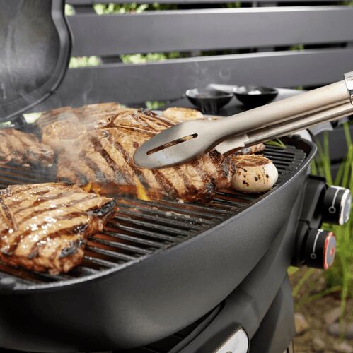 Carne asada a la parrilla con pinzas de cocina.