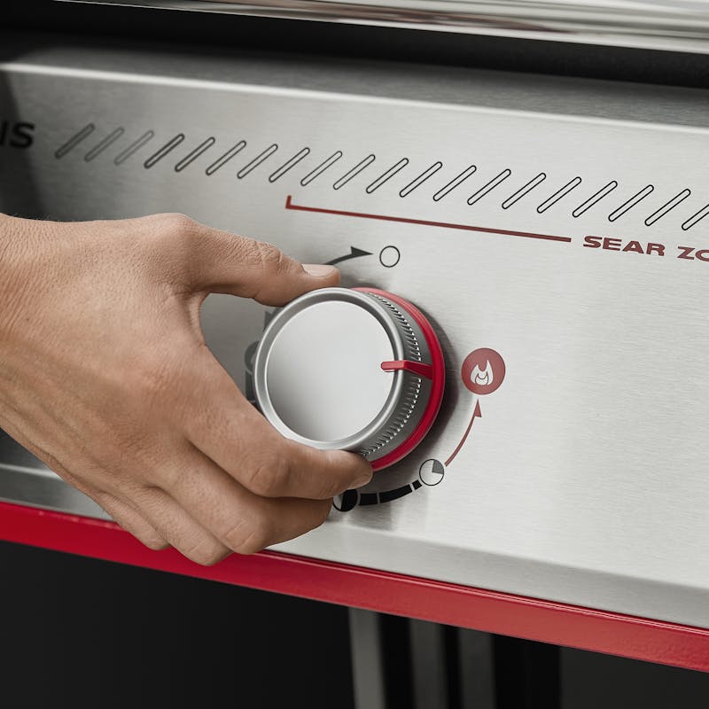 Mano ajustando perilla de control de barbacoa.