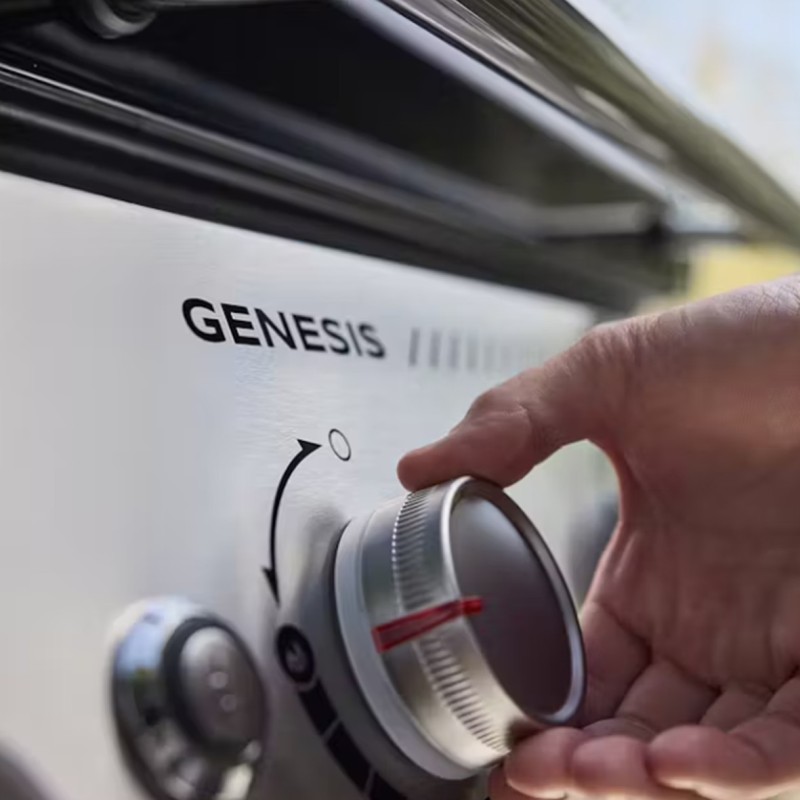 Mano ajustando el mando de una barbacoa Genesis