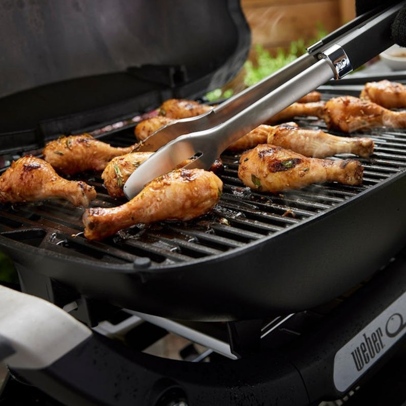Pollo asado en parrilla con pinzas de cocina