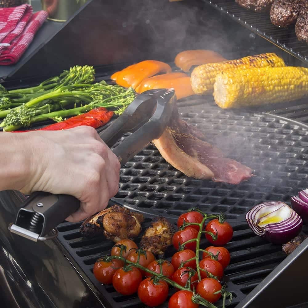 Persona asa carne y verduras en parrilla.