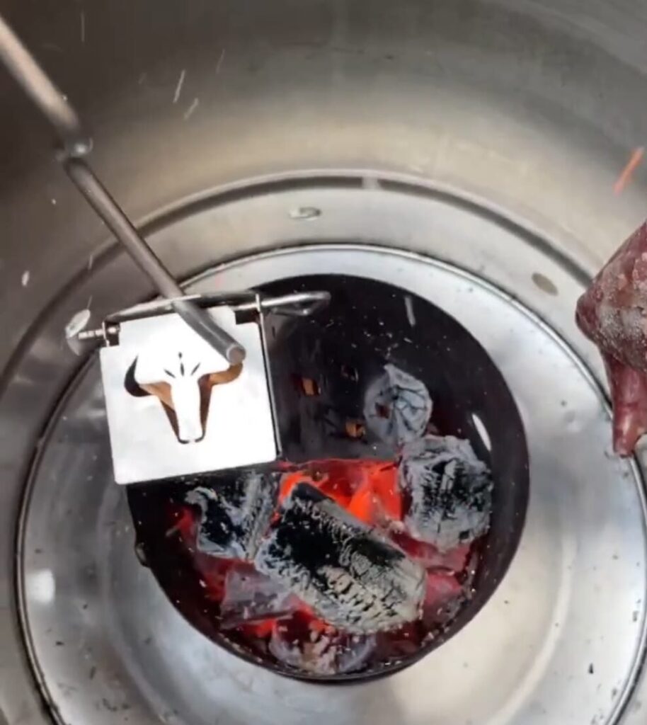 Carbón ardiendo en parrilla metálica con herramienta.