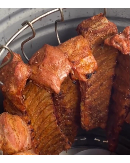 Costillas de cerdo asadas en barbacoa vertical.