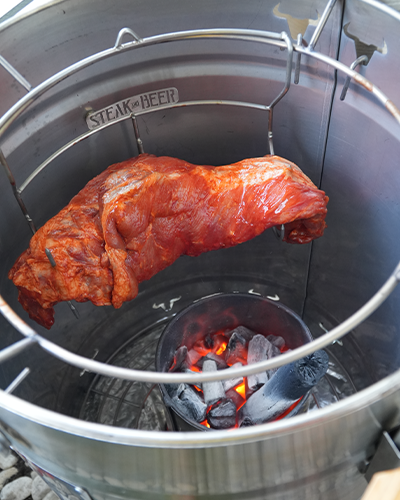 Carne asándose al carbón en asador vertical.
