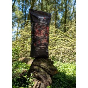 Bolsa de carbón sobre tronco en el bosque.