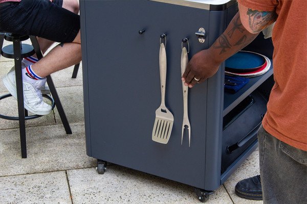 Hombre junto a carrito con utensilios de barbacoa
